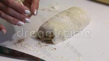 一个女人用一把刀切成一个擀面团，用来做朱砂。 附近有烹饪工具